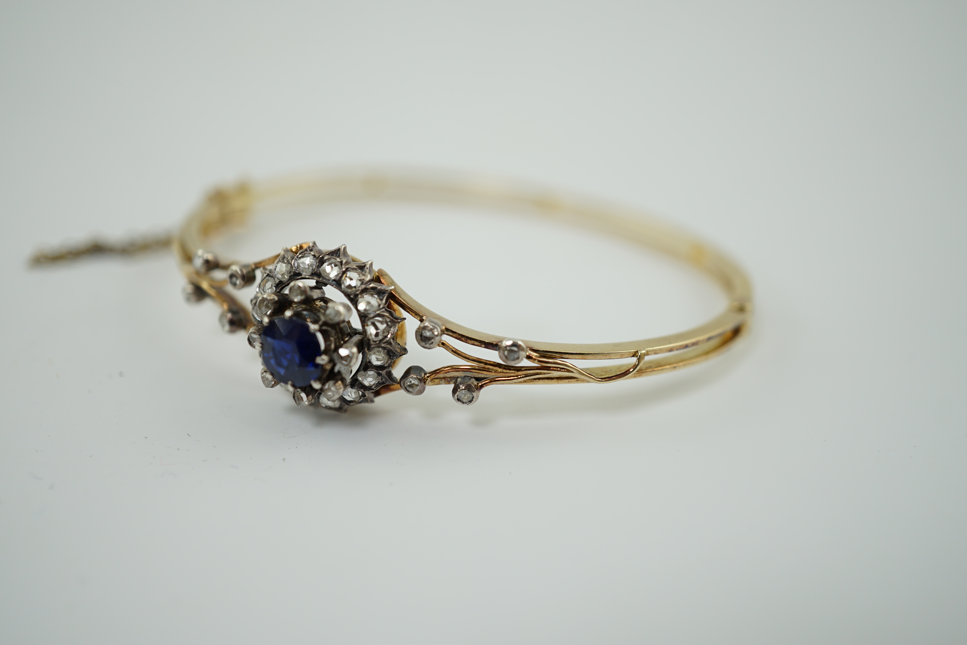 A Victorian gold, sapphire and diamond cluster set hinged bangle